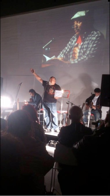 Fotografía de Julia González, con Felipe Zapico y Delta Galgos, e imágenes de Juan Luis García sobre la pared.