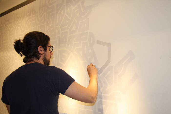 Lio pintando el laberinto de las paredes sobre las que ha colgado los cuadros. Foto: Ana Blanco.